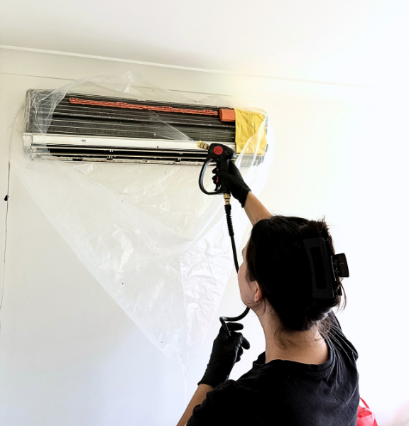 Courteney from AirEffect servicing a heat pump on a ladder
